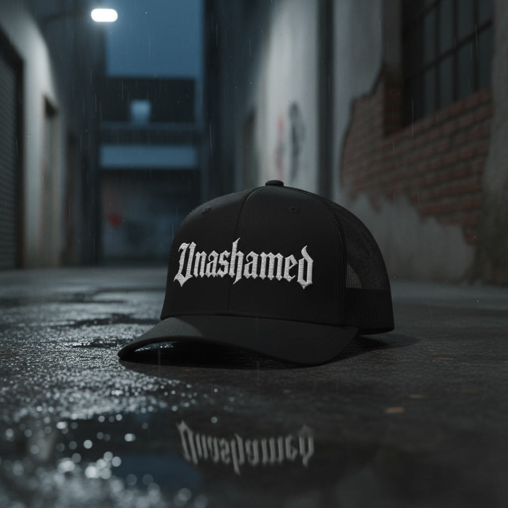 Black trucker hat with Unashamed across the front panel