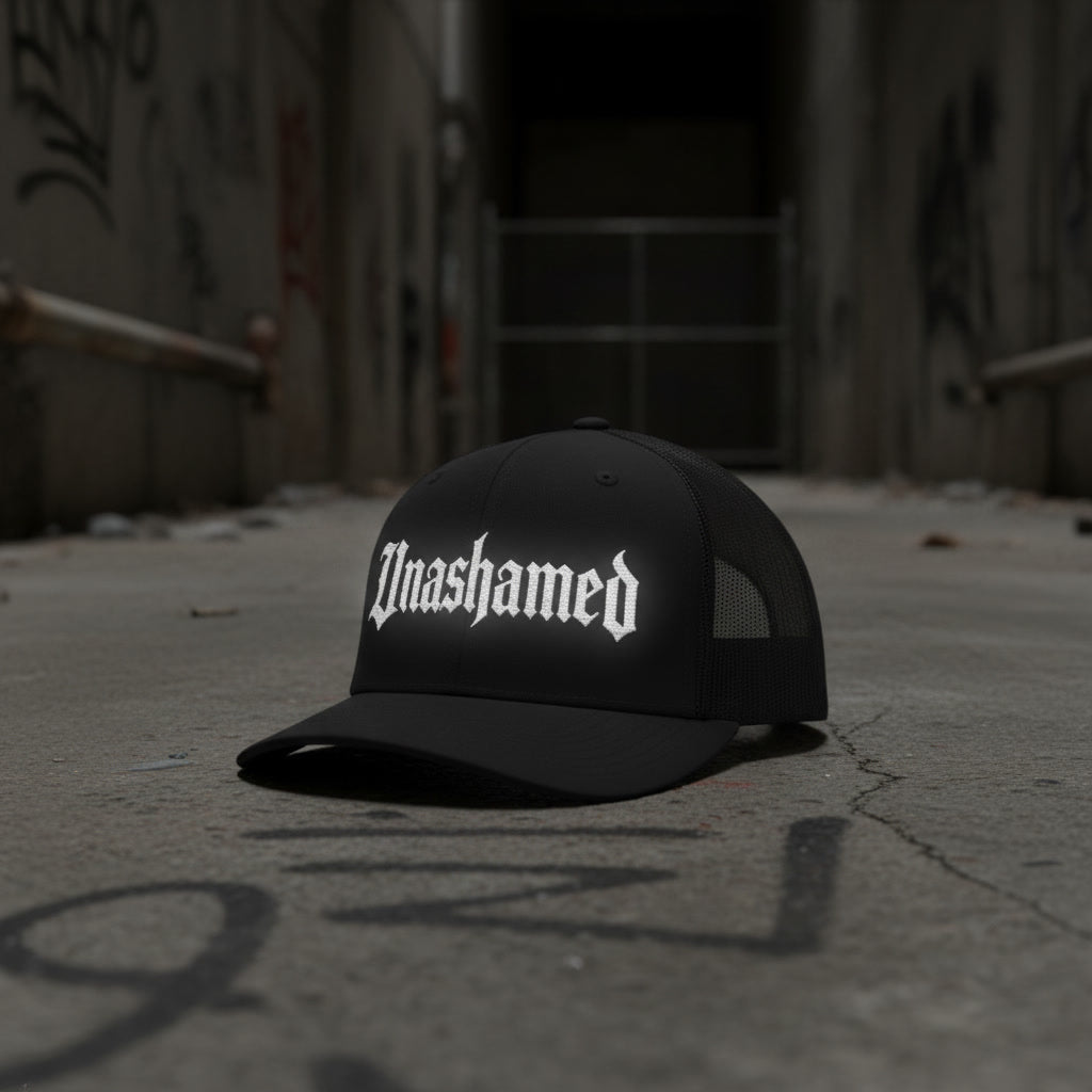 Unashamed trucker hat in black with white lettering